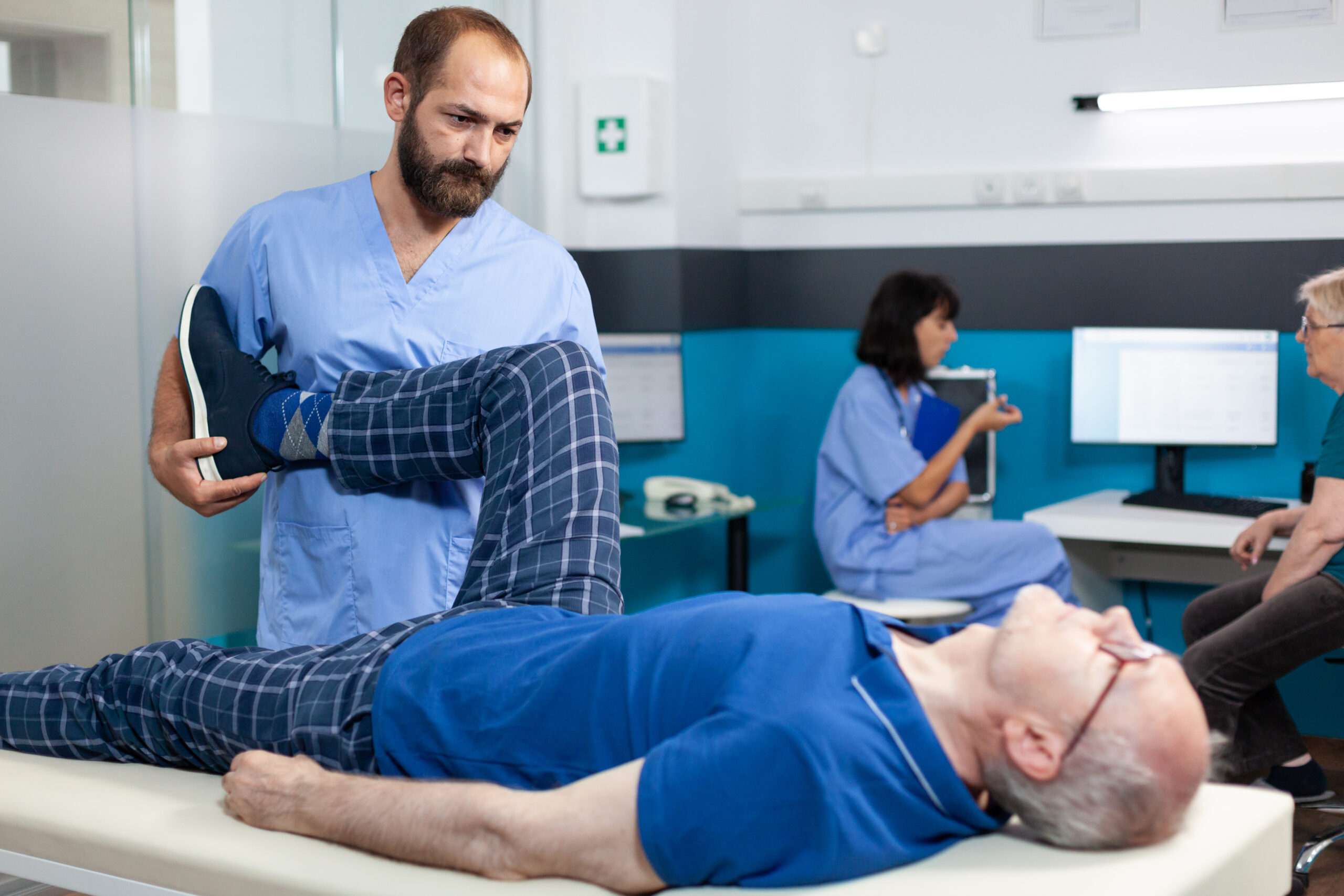 Orthopedic specialist assisting an elderly patient with a leg joint injury during post-surgery rehabilitation